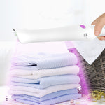 Travel sterilization lamp stick in white ABS material with purple button emitting UV light over folded towels for disinfection.